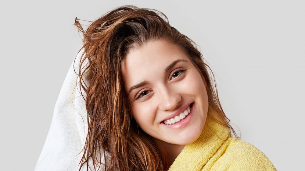 femme heureuse séchant ses cheveux mouillés avec une serviette dans un peignoir jaune 