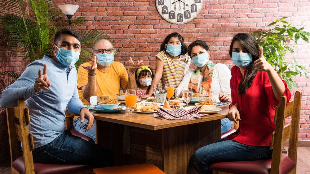 Famille au restaurant portant des masques faciaux