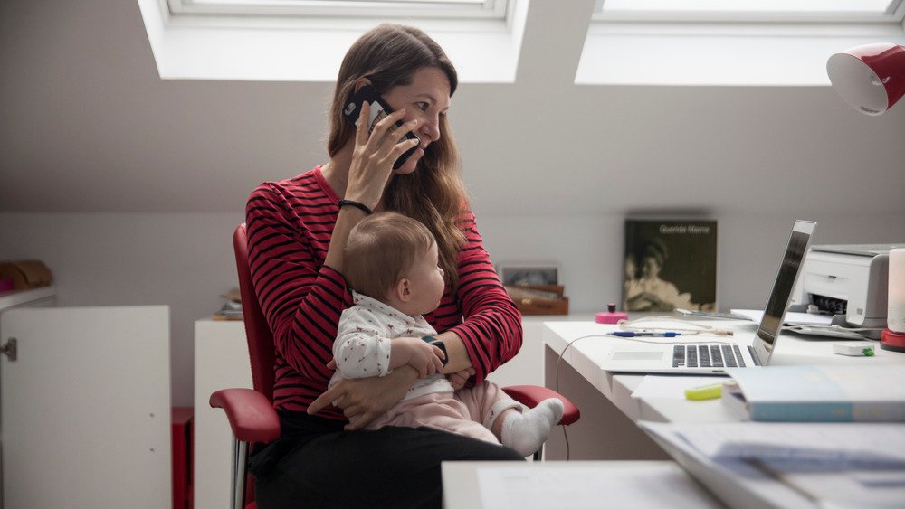 Femme devant un ordinateur portable sur un téléphone avec un bébé sur ses genoux