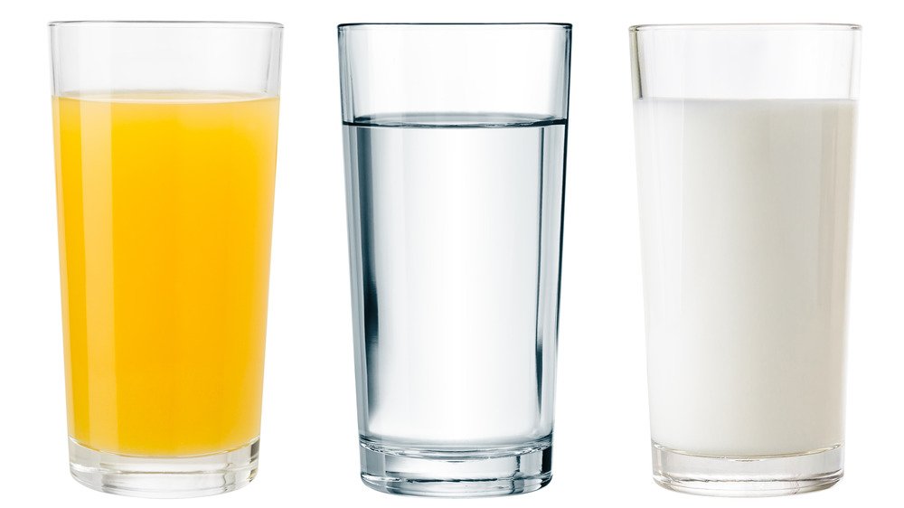 Verres d'eau, de lait et de jus sur fond blanc