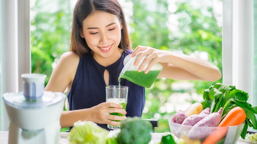 Jeune femme versant du jus vert