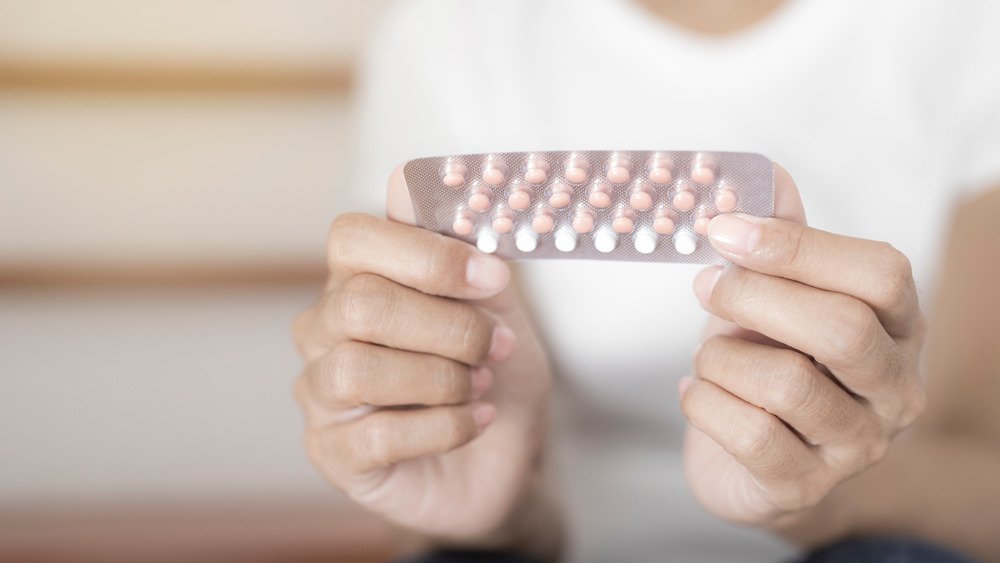 Gros plan d'une femme tenant des pilules contraceptives