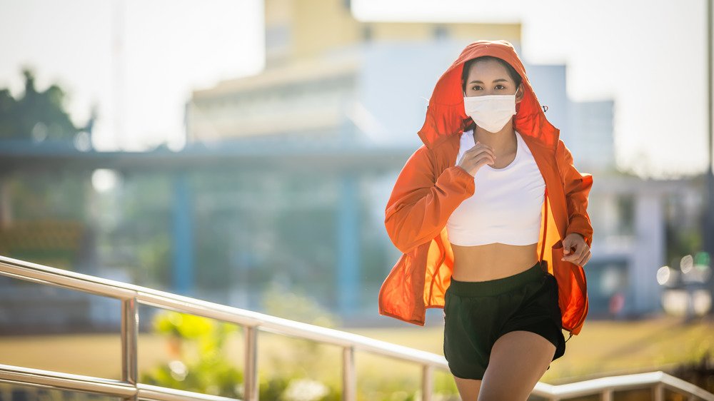 Une jeune femme fait du jogging tout en portant un masque facial