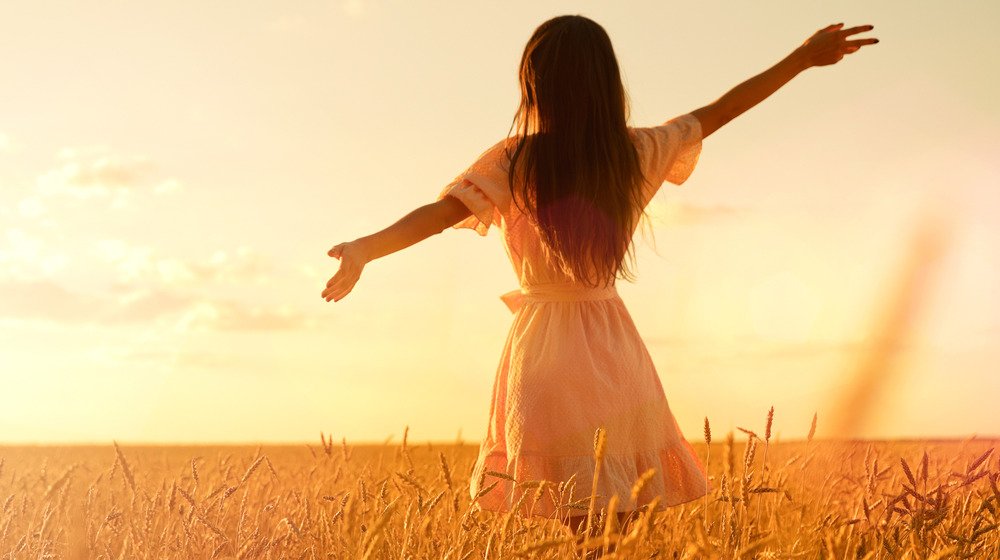 Personne aux cheveux longs debout dans un champ de blé