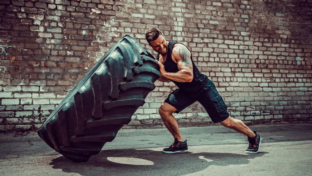 homme renversant un pneu dans une salle de sport