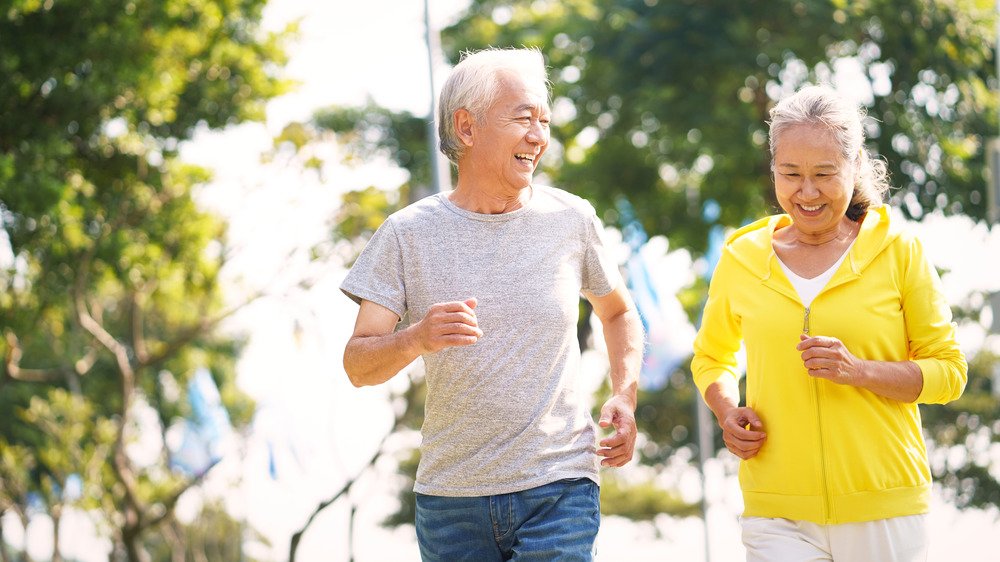 Un couple asiatique âgé fait du jogging ou marche rapidement à l'extérieur