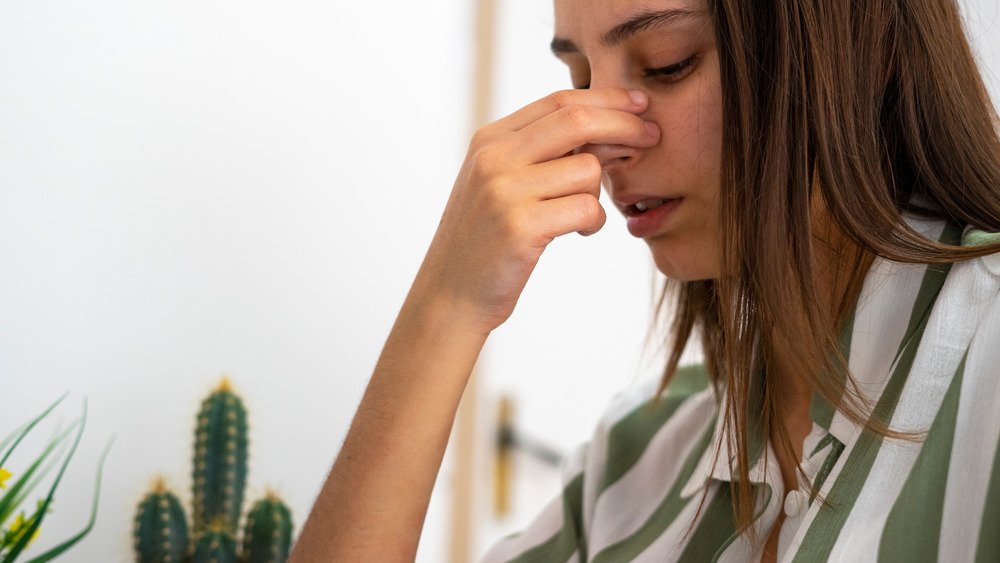 Femme regardant vers le bas et se pinçant l'arête du nez 