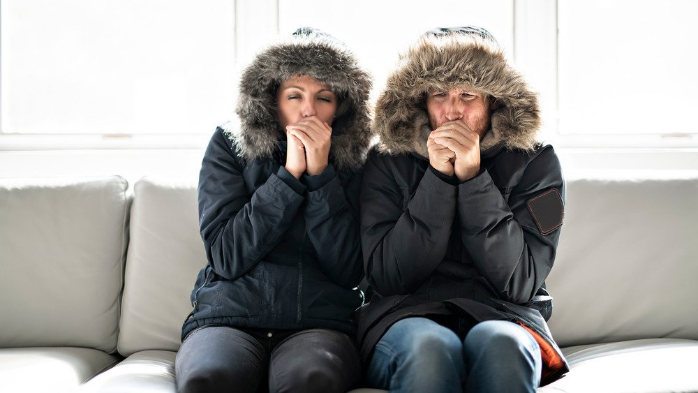 Couple assis sur un canapé avec des manteaux d'hiver