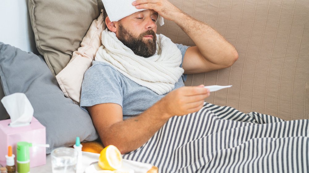 Un homme tenant un tissu sur le front et vérifiant la température