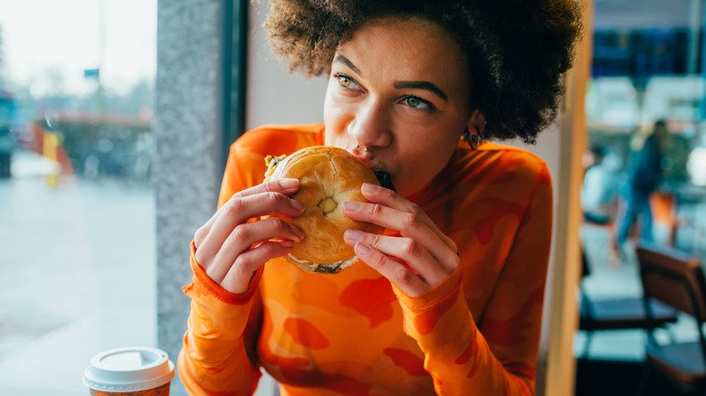 Une femme mange un bagel dans un café