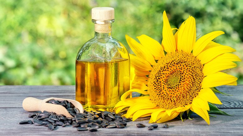 Bouteille d'huile de tournesol à côté d'un tournesol