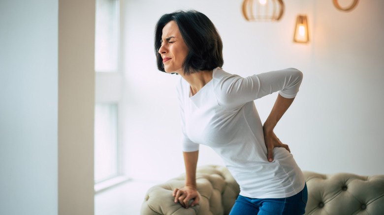 Une femme se tient le bas du dos en raison de la douleur