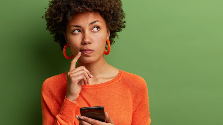 Femme pensant et tenant un téléphone