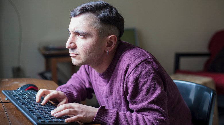 Personne penchée sur un bureau en train de taper