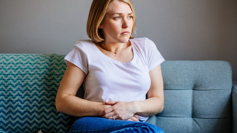 femme tenant son ventre assise sur le canapé