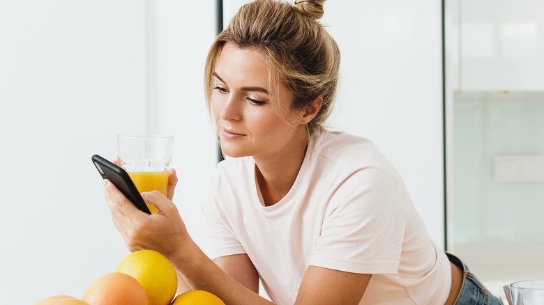 Femme regardant un téléphone tenant du jus