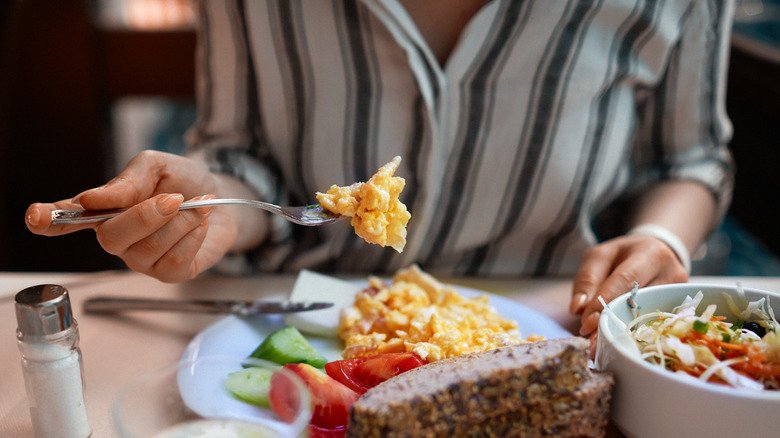 Main tenant une fourchette avec des œufs brouillés