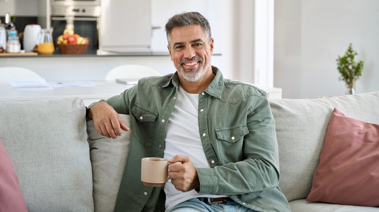 Homme d'âge moyen souriant tenant une tasse