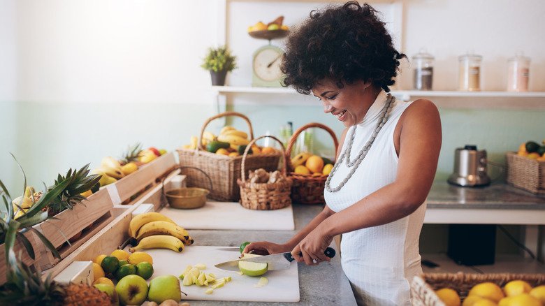 Femme souriante coupant des fruits