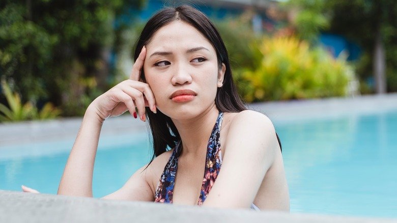 Jeune femme attendant au bord de la piscine