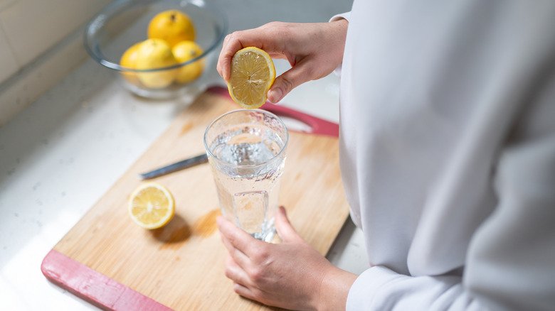 femme pressant un citron dans l'eau