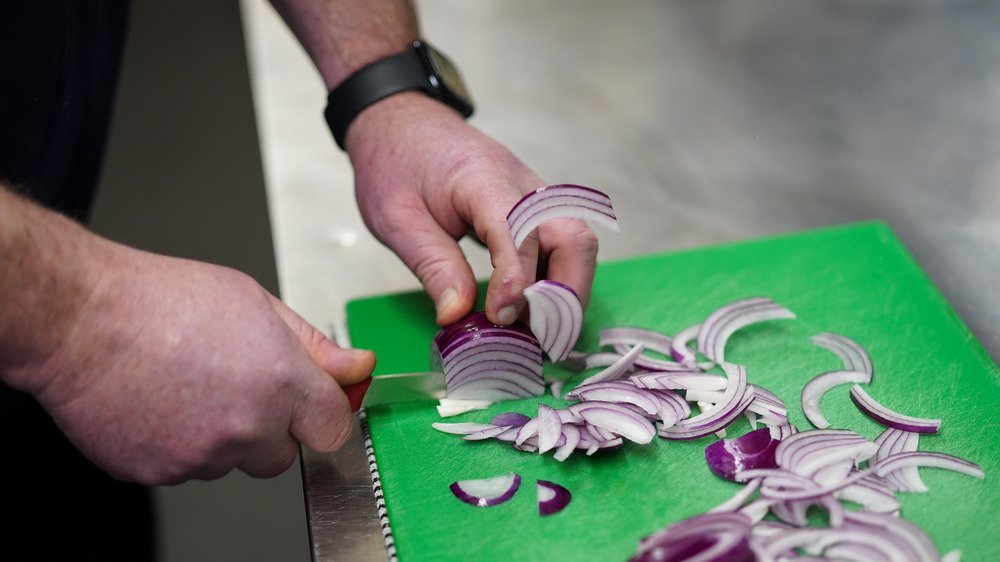 Le chef Colin Woodward hache un oignon pendant qu'il prépare des repas au restaurant Mill le 28 octobre 2020 à Stokesley, en Angleterre.