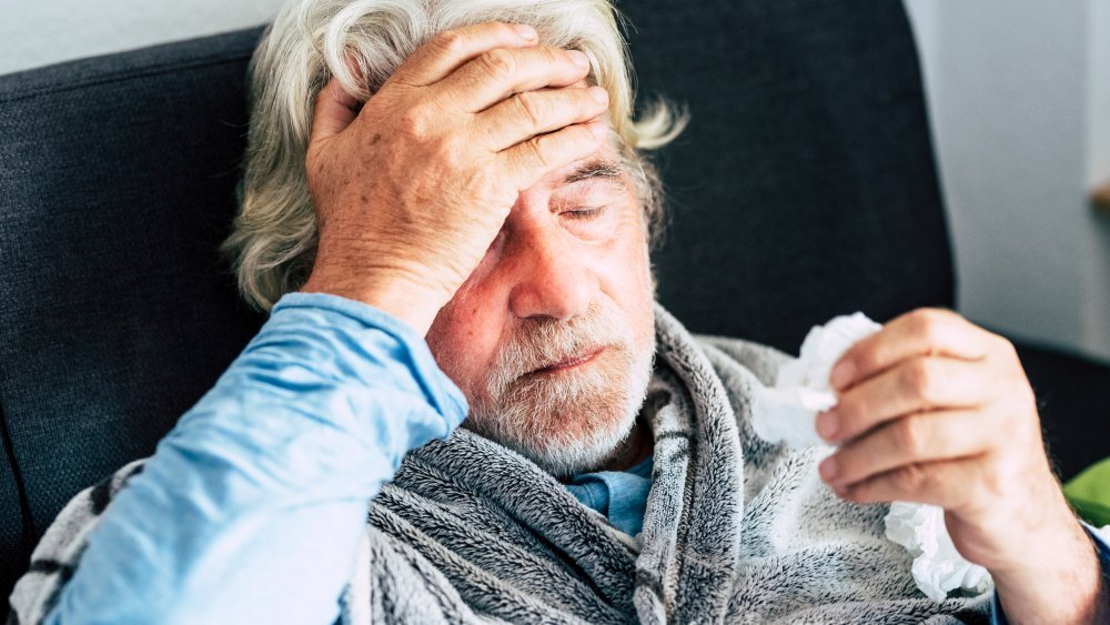 Un homme âgé en robe de chambre présente des symptômes de rhume