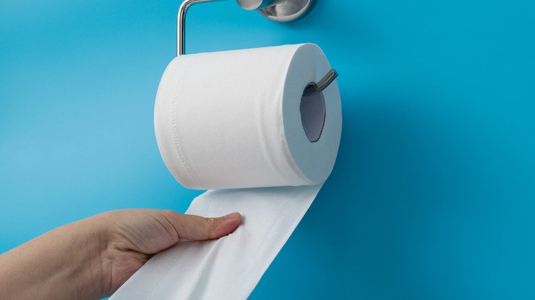 main d'une femme tendant la main vers le papier toilette