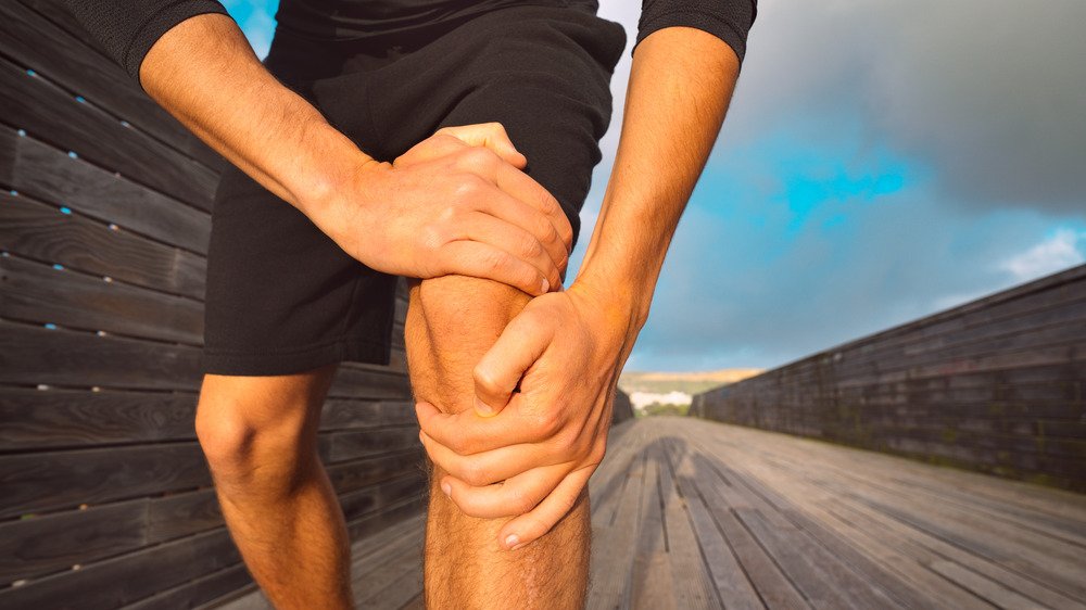 Courir en saisissant le genou dans la douleur 