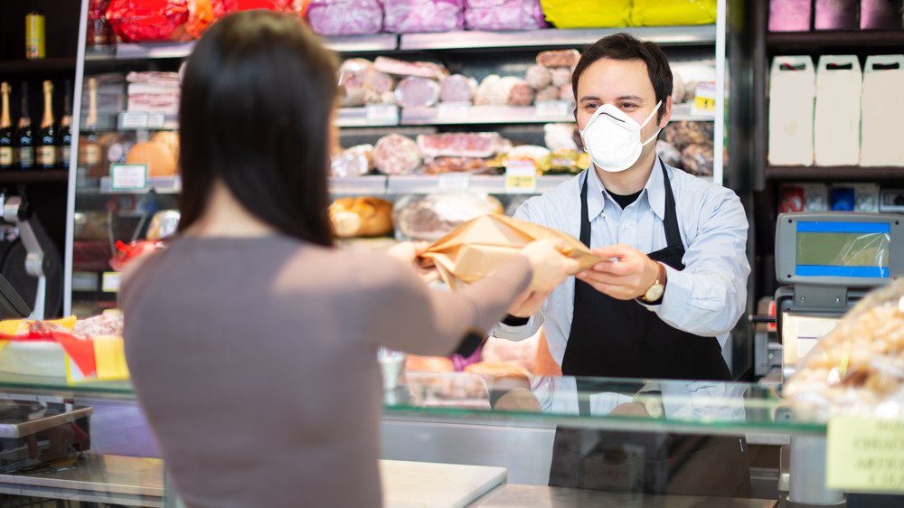 Employé d'une épicerie portant un masque facial