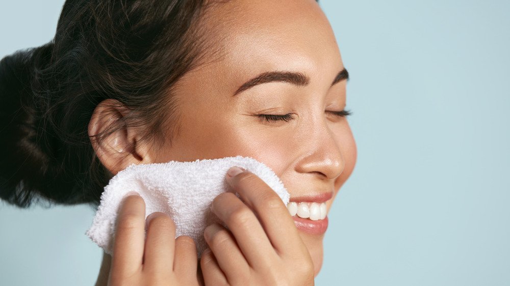 femme nettoyant le visage avec un gant de toilette