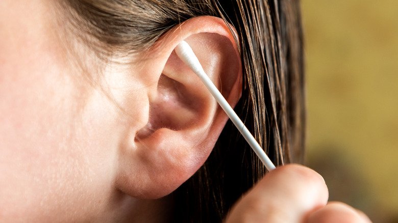 Femme nettoyant la partie externe de l'oreille avec un coton-tige