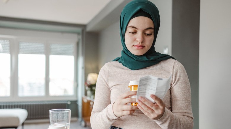 Une femme lit un avertissement concernant un médicament sur ordonnance