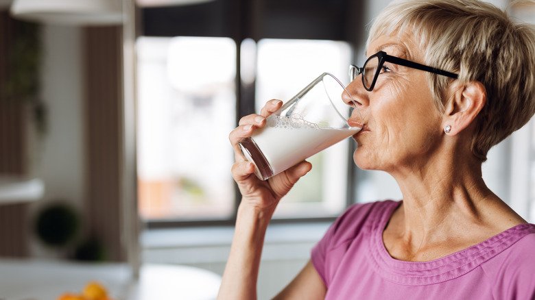 femme âgée avec des lunettes buvant du lait