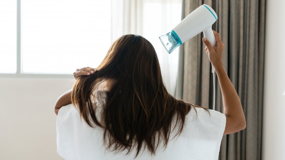 une femme en peignoir se séchant les cheveux 