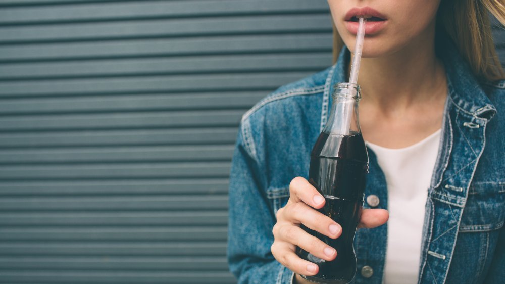 Gros plan d'une femme buvant du soda dans une bouteille avec une paille