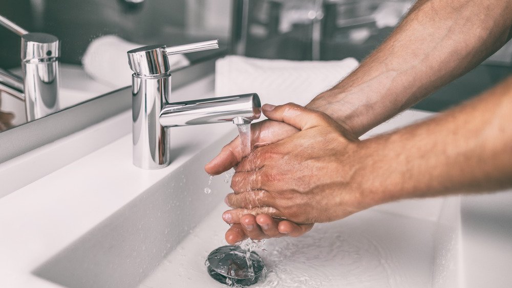 homme se lavant les mains au lavabo 