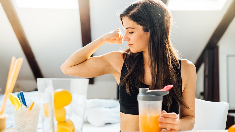 Femme buvant du jus et fléchissant ses biceps