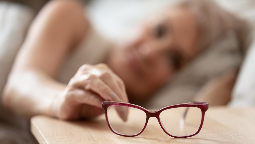 Une femme se réveille et prend ses lunettes