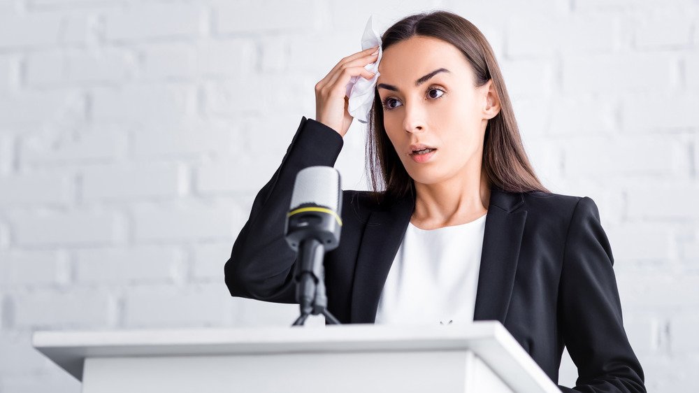 Une femme sur un podium s'essuie la sueur du front