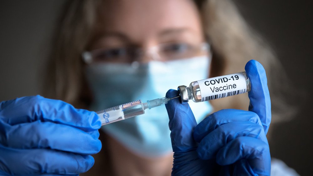 Une femme tenant un vaccin contre la COVID