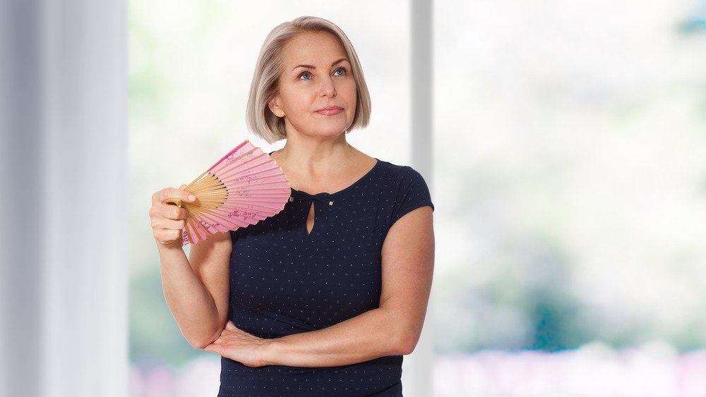 Femme d'âge moyen debout s'éventant