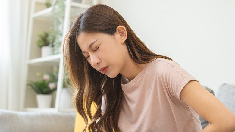 Une jeune femme se tient le ventre en signe de douleur