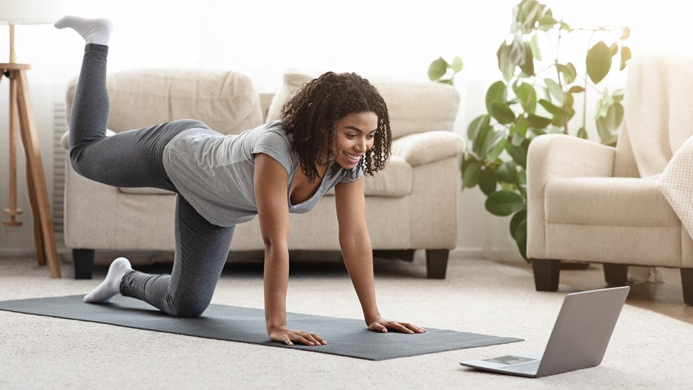 Photo d'archives d'une jeune femme prenant une pose de yoga en regardant un cours en ligne