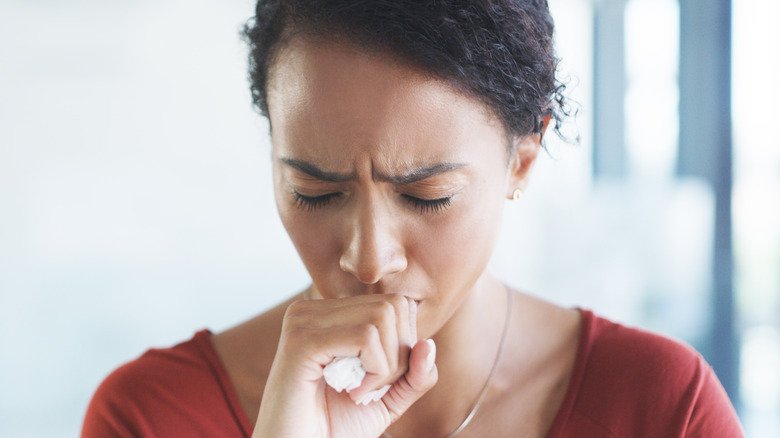 Jeune femme se couvrant la bouche en toussant