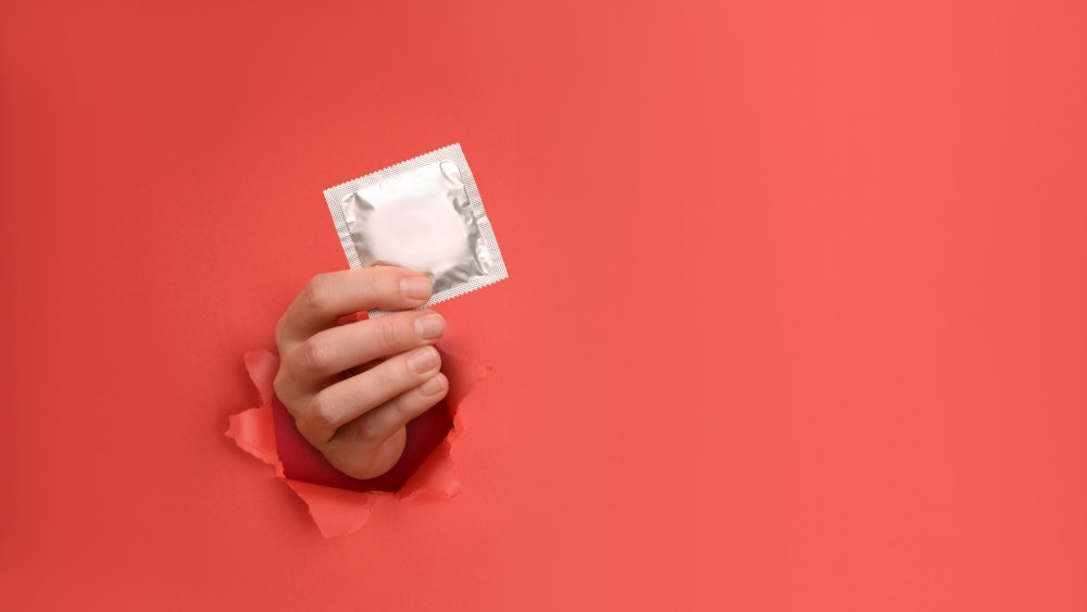 Une main tient un préservatif, un type de contraception