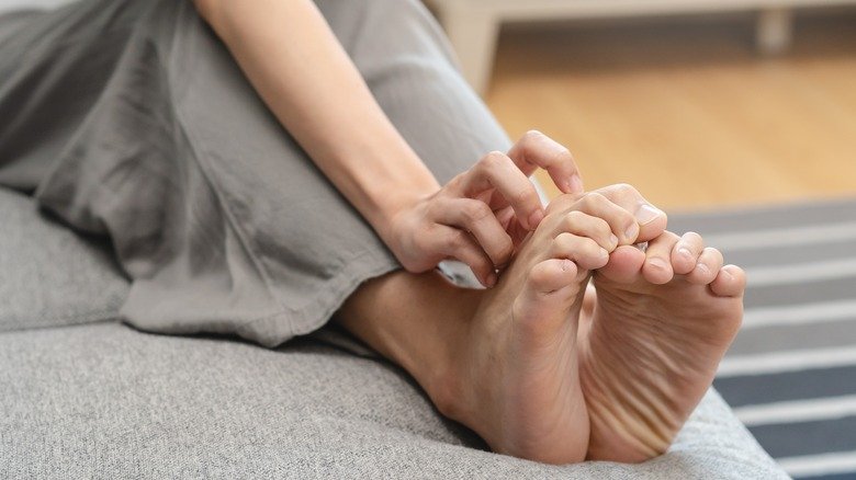 Femme se grattant les pieds qui démangent