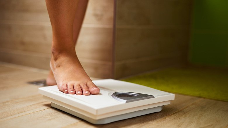 Les pieds d'une femme marchant sur une balance