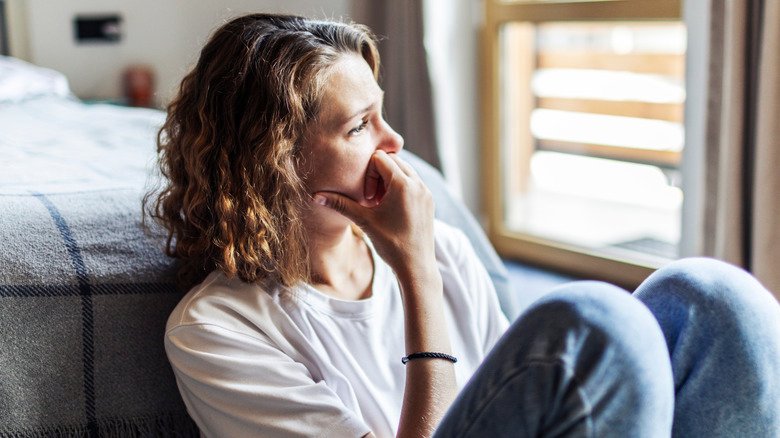 Jeune femme regardant tristement par la fenêtre