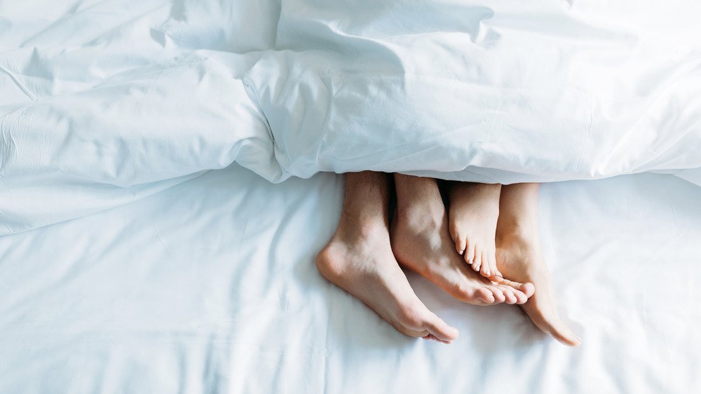 Les pieds d'un couple au lit